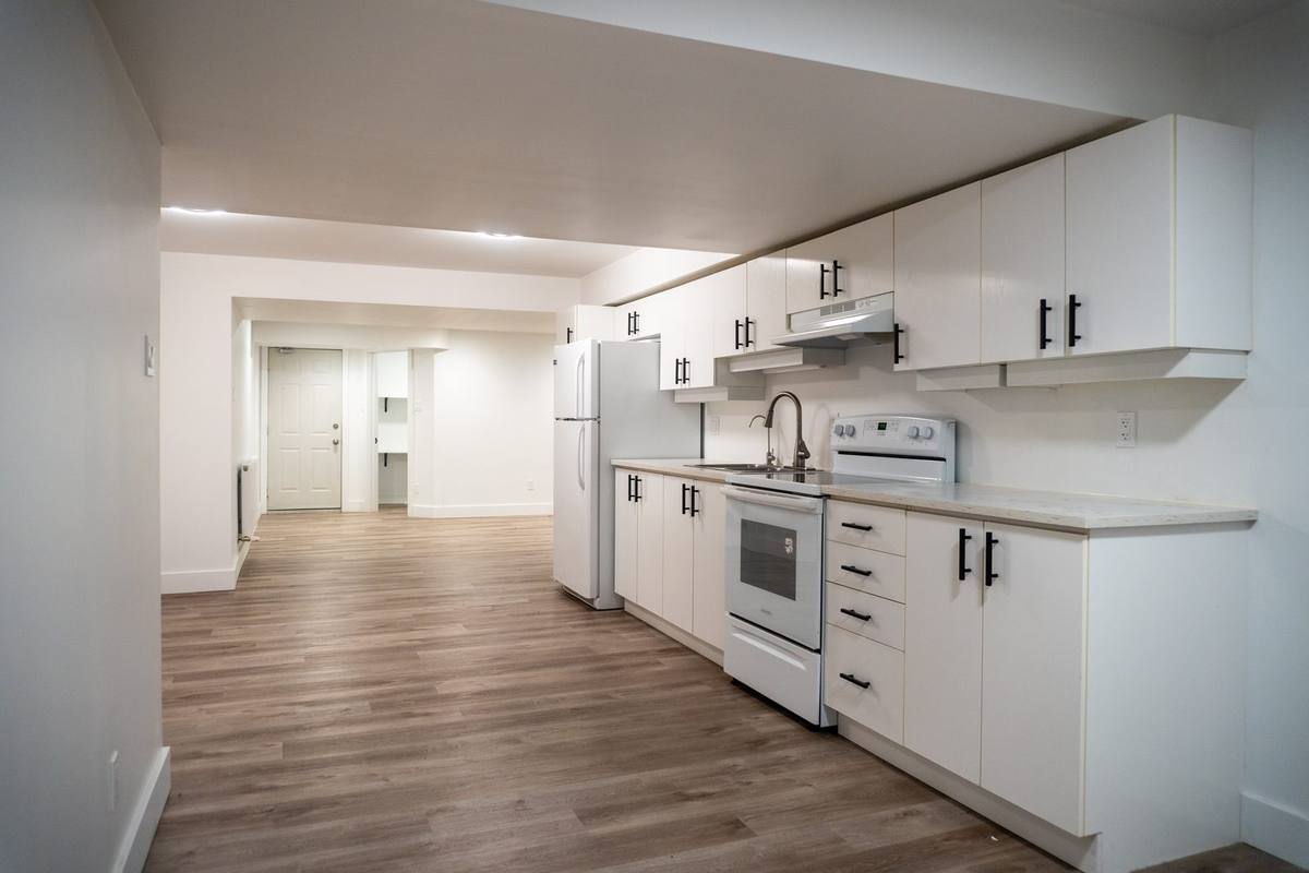 Basement apartment in Navan with a full white kitchen, vinyl plank floors and pot lights