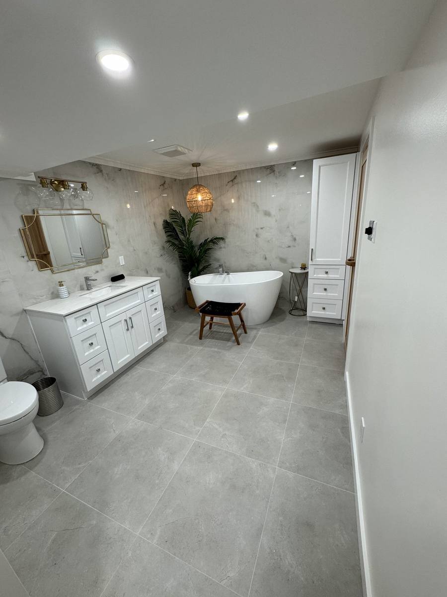 Basement spa bathroom in Navan with freestanding tub, white vanity and marble-look slab tile walls